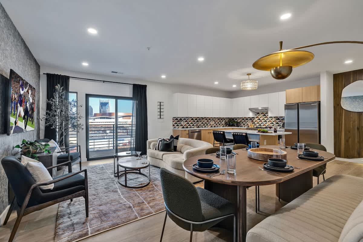 Bright open living space featuring smart flat-screen TV, designer furnishings, and access to a large corner private balcony.