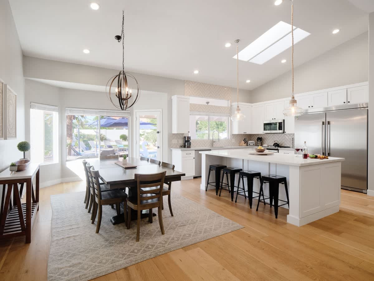 Fully equipped kitchen with stainless steel appliances, a sleek kitchen island with a breakfast bar for casual seating for 4, plus a large dining table for 8. (1st Floor)