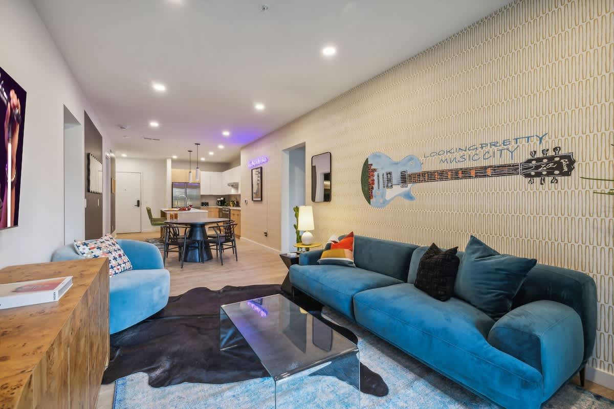 Warm and stylish living room featuring a large Smart TV, elegant furnishings, and a spacious balcony.