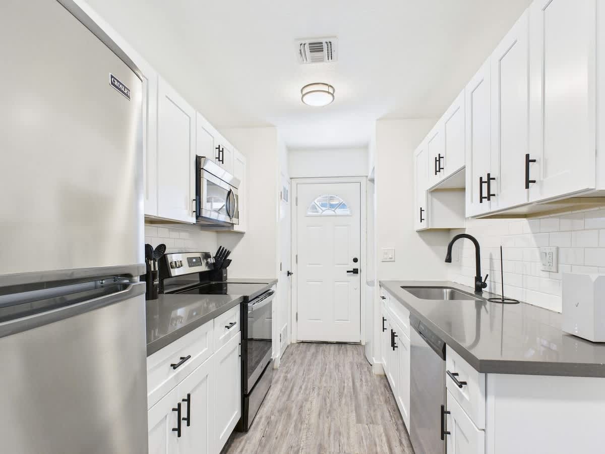 Fully equipped kitchen stocked with basic cooking essentials, stainless steel appliances, access to the shared backyard, and a washer and dryer.