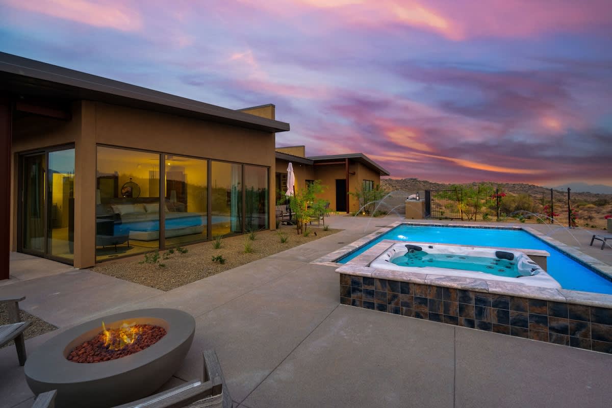 Estate 1: Stunning private oasis featuring a sparkling blue pool with sun loungers, a patio with a BBQ grill, outdoor furnishings for lounging and dining, and a fire pit surrounded by unparalleled des