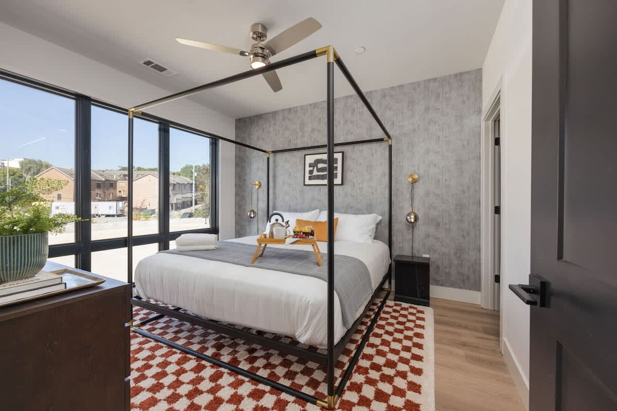 The primary bedroom is a lavish sanctuary featuring a spacious King bed and floor-to-ceiling windows. It's equipped with a Smart TV for entertainment, a luxurious en-suite bathroom for convenience, an