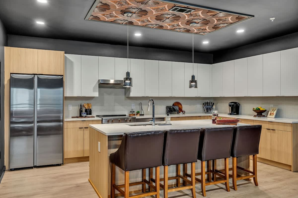 The fully equipped modern kitchen features culinary essentials, stainless steel appliances, and island bar seating.