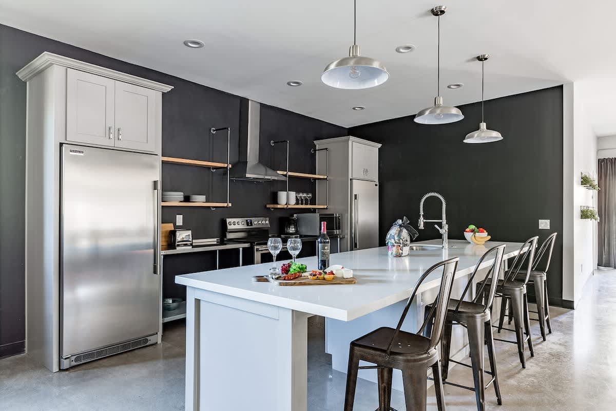 Unit 1: Fully equipped modern kitchen featuring stainless steel appliances, kitchen island with bar seating for 4 guests and a formal dining table with seating for 8 guests.