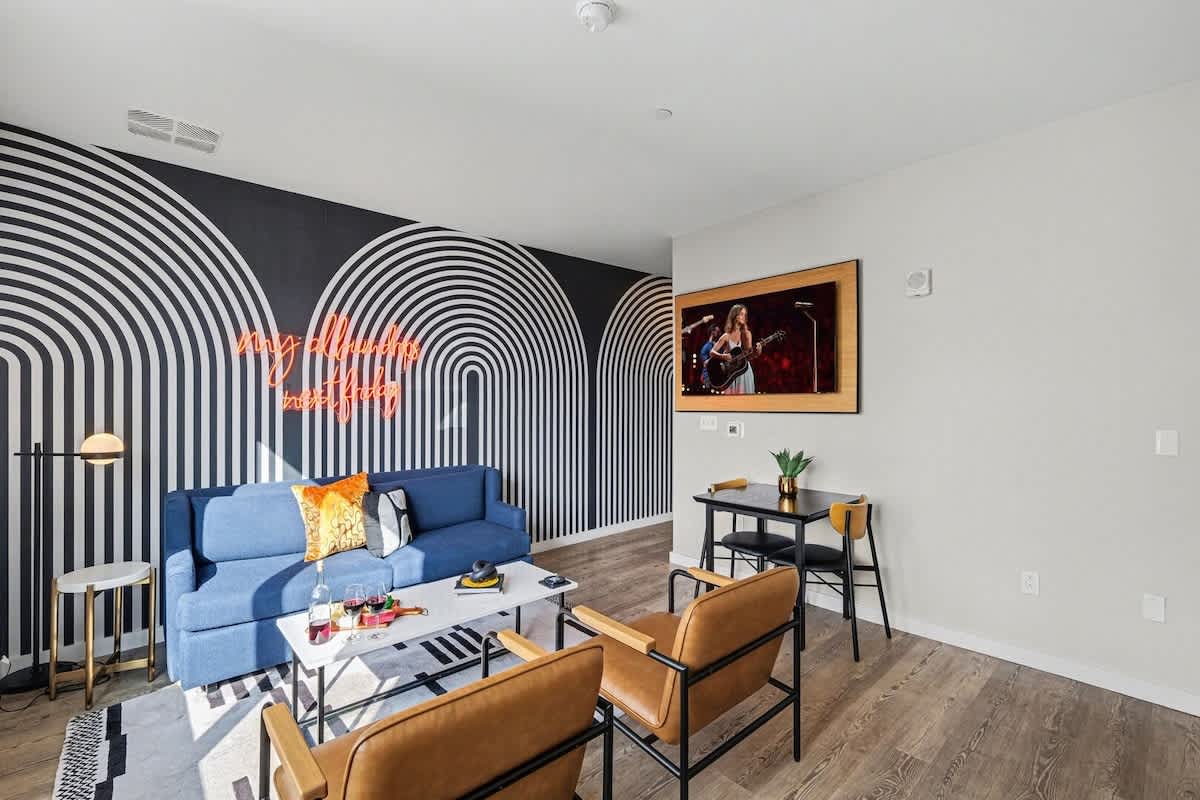 Unit 2: Bright open floor living space featuring a smart flat-screen TV and designer furnishings. Connects to the dining area and kitchen.