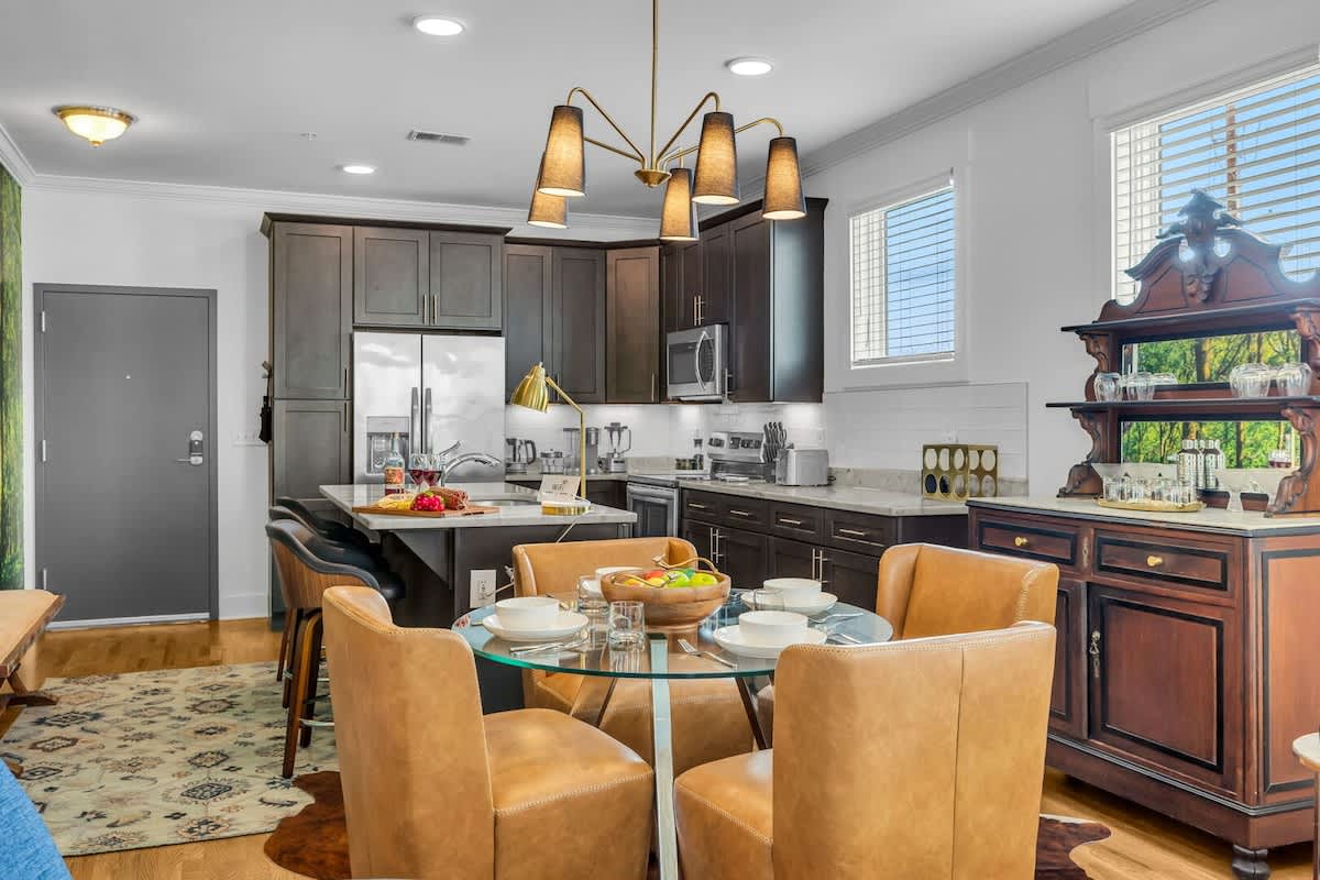 The dining area features a table for four and a hutch with cocktail-making utensils and drinkware, perfect for unwinding after a day of exploring. Overlooking the fully equipped kitchen.
