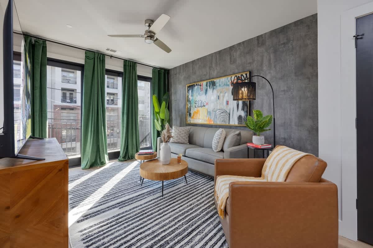 Bright open living space featuring a smart flat-screen TV, designer furnishings, and access to the patio.
