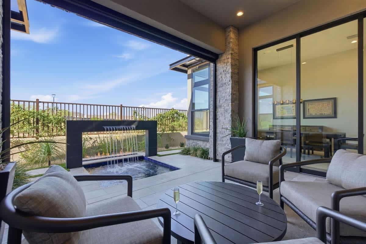 Back Patio with covered lounge and motorized screen, hot tub with waterfall, in-ground fire pit, and built-in grill for ultimate outdoor relaxation.