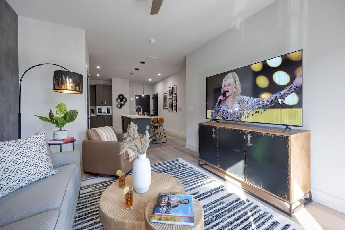 Bright open living space featuring a smart flat-screen TV, designer furnishings, and access to the patio.