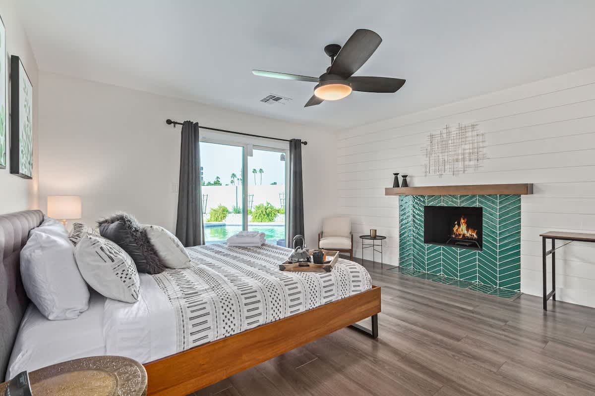 Primary bedroom with King bed, patio access, an en-suite walk-in shower with triple showerheads, soaking tub, and large walk-in closet space.
