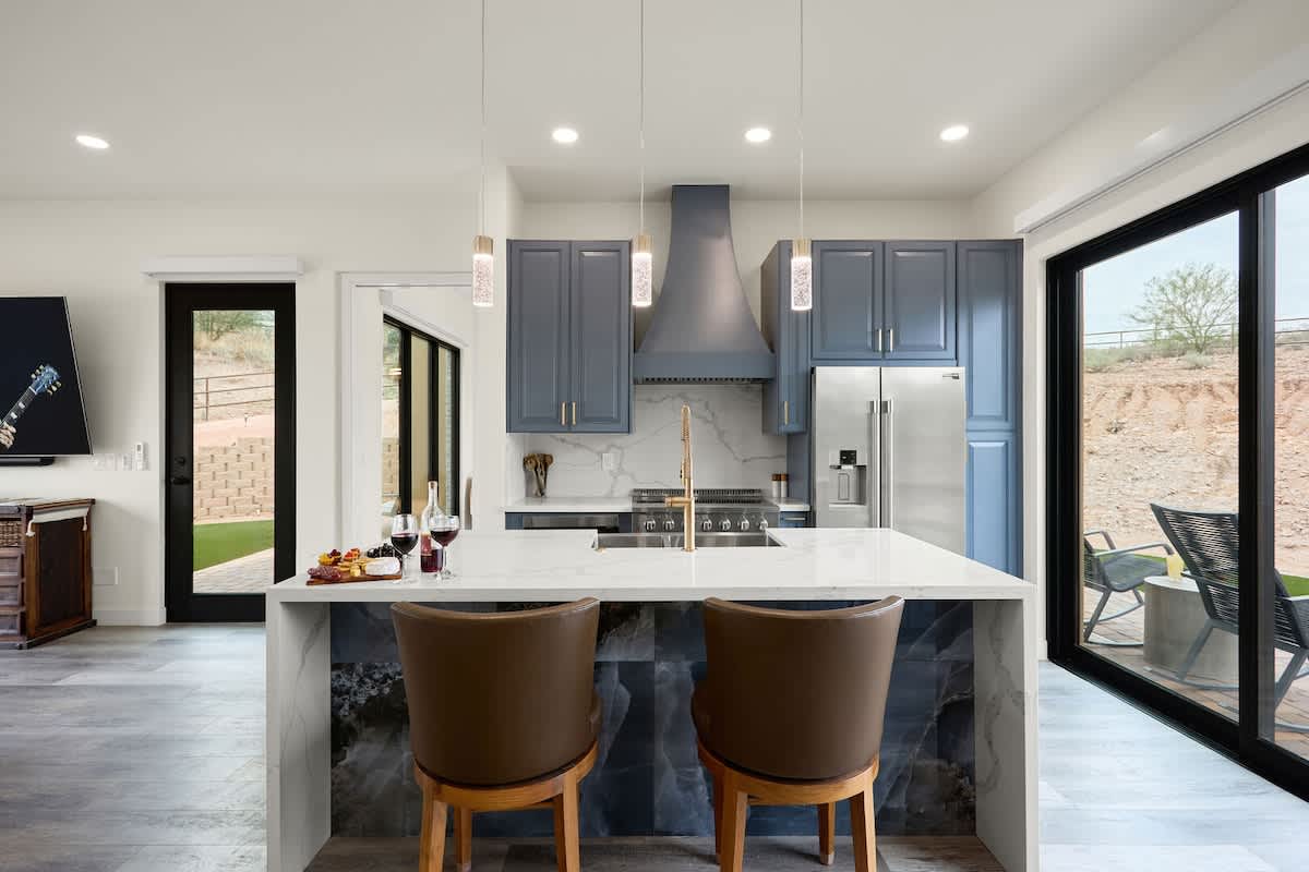 Fully equipped kitchen with stainless steel appliances, a sleek kitchen island with a breakfast bar for casual seating for 2.