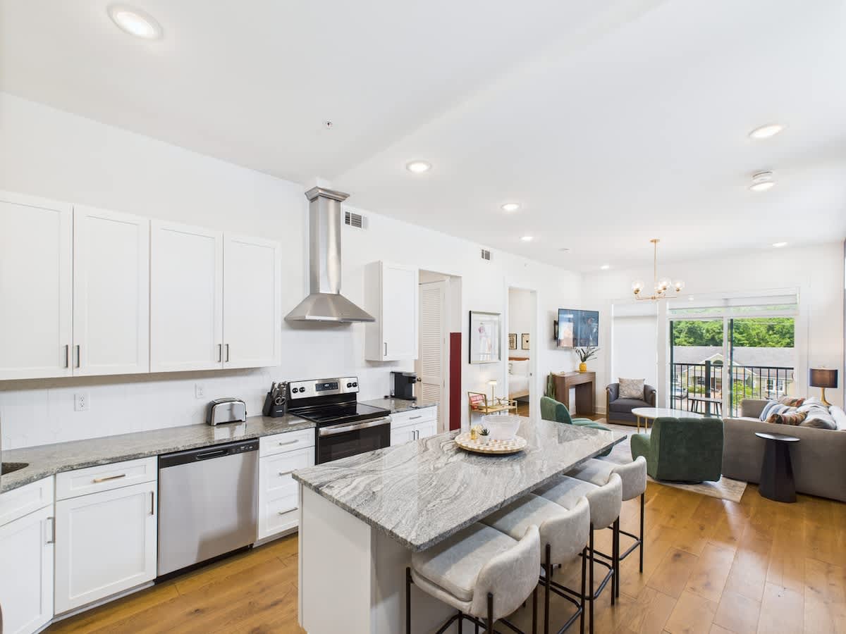 The fully equipped modern kitchen features culinary essentials, stainless steel appliances, and island bar seating.
