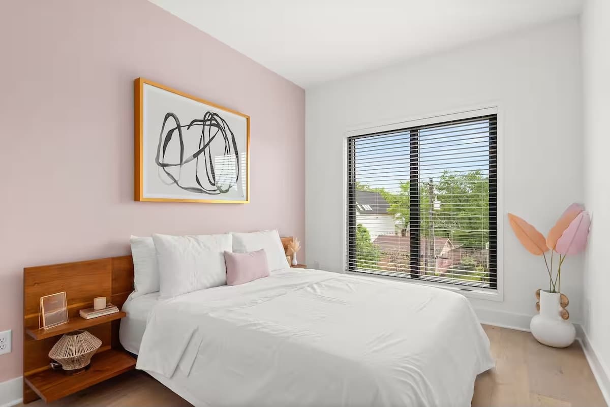 Inviting 2nd bedroom with a queen bed, blush accent wall, modern artwork, and a large window for plenty of natural light. (3rd Floor)