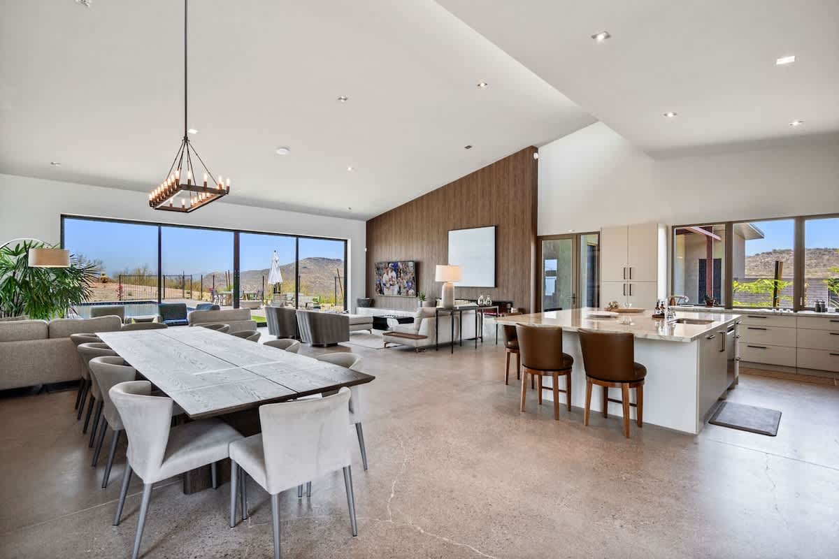 Fully equipped luxury kitchen stocked with all culinary essentials and features high-end stainless-steel appliances, a kitchen island, a dining table, and a wet bar/coffee station.