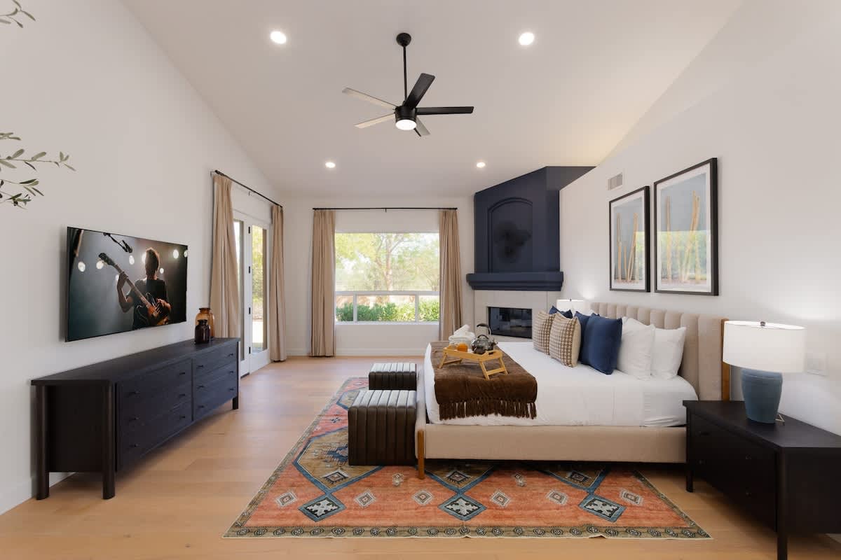 Primary Bedroom featuring a King bed, designer furnishings, fireplace, large walk in closet, en-suite bathroom, and backyard access.
