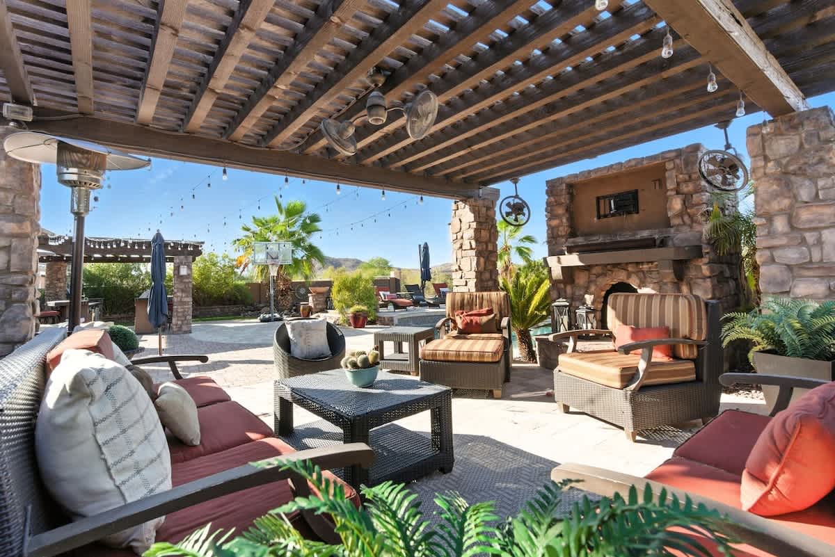 Outdoor pergola with multiple lounge areas, fireplace, fans, and outdoor heaters.