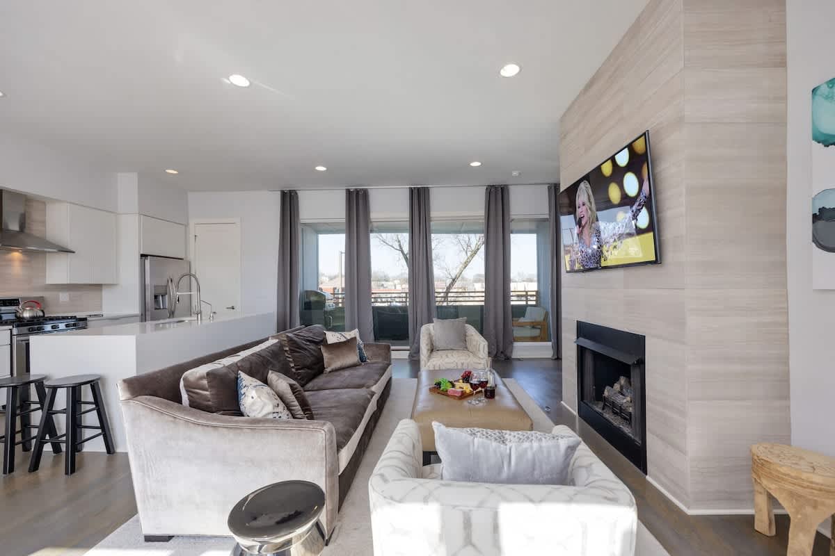 Bright open floor living space featuring designer furnishings, a smart TV, a fireplace, and access to a private balcony. (2nd Floor)