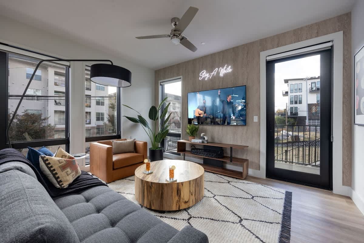 Bright open living space featuring a smart flat-screen TV, designer furnishings, and access to the private patio.