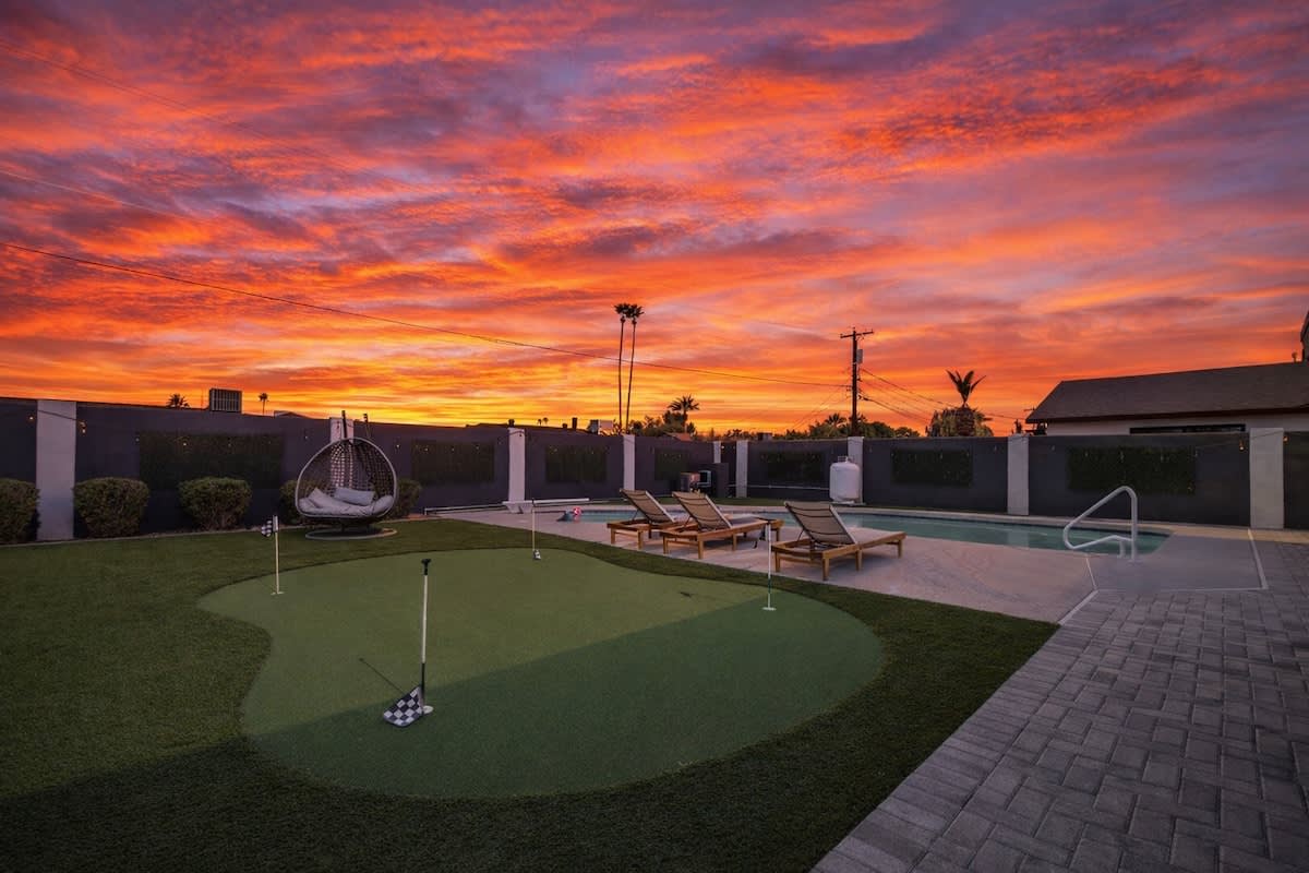 Private backyard featuring a sparkling pool, sun loungers, mini golf, and a covered patio with outdoor seating, and a BBQ grill.