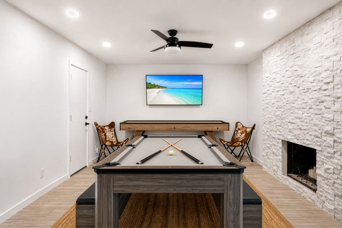 Game room and dining area featuring a versatile 3-in-1 table that easily converts between pool, ping pong, and dining, alongside a shuffleboard and a smart TV for nonstop entertainment.