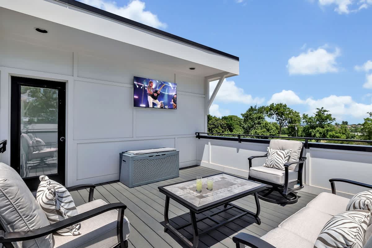 4th Floor: Private rooftop patio featuring outdoor furnishings for lounging and a Smart TV for entertainment surrounded by beautiful neighborhood views.