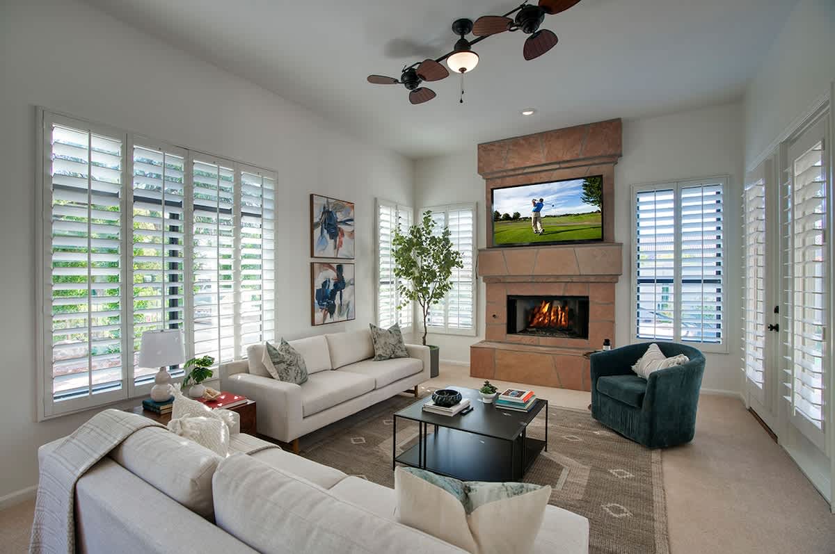 Bright open floor primary living area, modern furnishings, smart TV, gas fireplace, doors to the private backyard, and easy access to the non-formal dining area and kitchen.