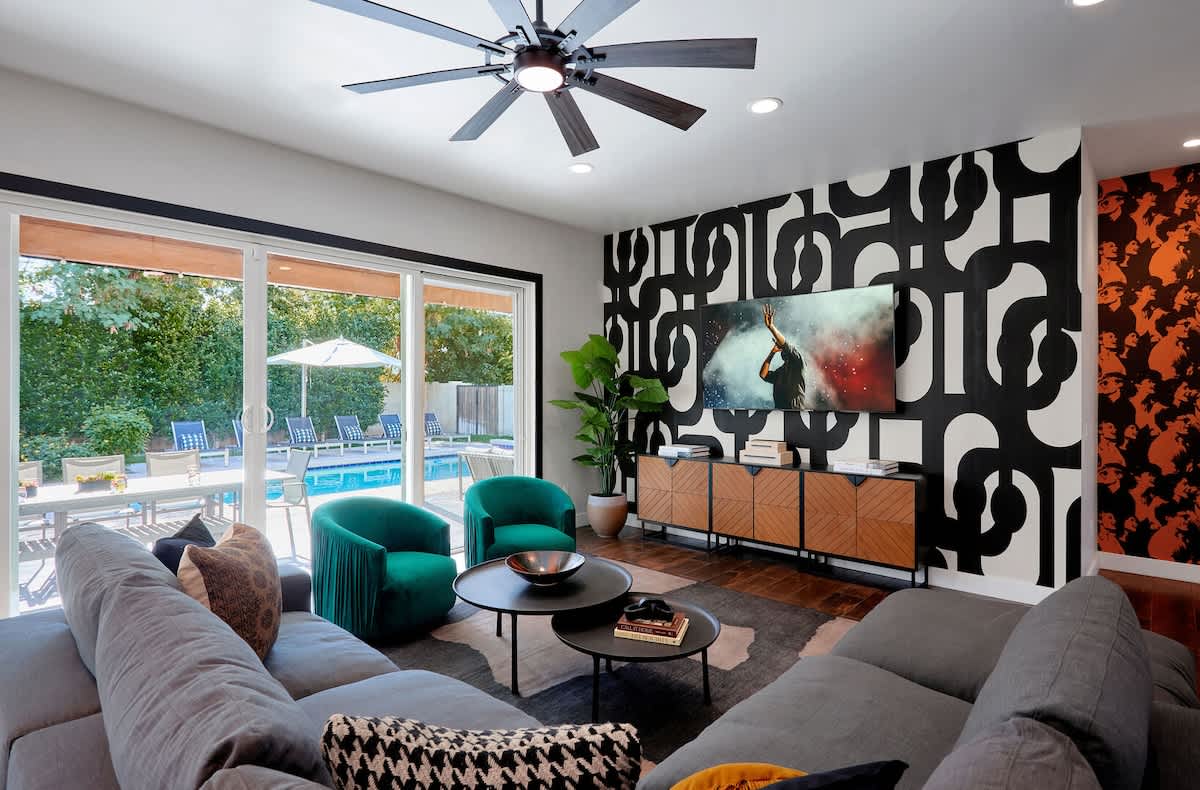 The living room offers a stylish, welcoming space with a roomy sectional, bold accent wall, cozy seating, and a smart TV for easy entertainment.