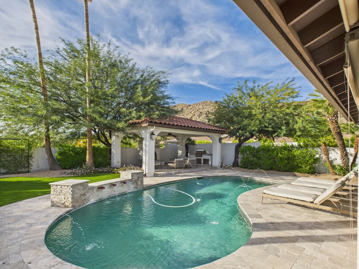 Outdoor oasis featuring a sparkling pool, lounge chairs, outdoor dining table, fire pit, and pergola with built-in BBQ grill. *Fireplace for display only.