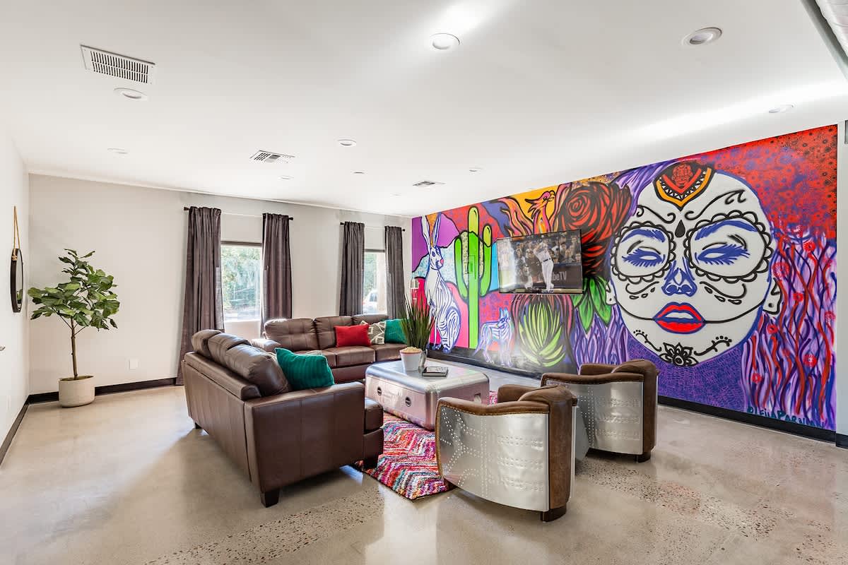 Unit 1: Open-floor living space featuring a Smart TV, designer furnishings, a beautiful mural on the wall, dining table, and a pool table.