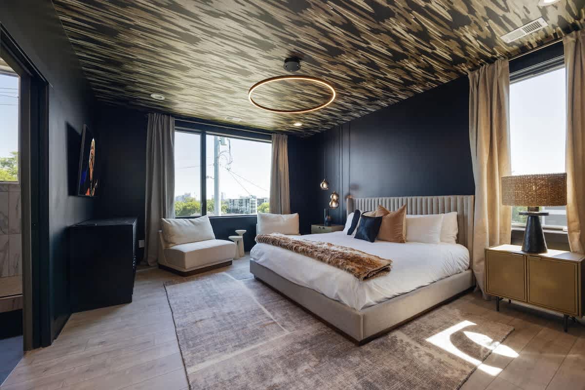 Upper Unit - 3rd Floor: Moody primary bedroom featuring designer furnishings including a King-size bed with a grand walk-in closet, a Smart TV and an ensuite primary bathroom.