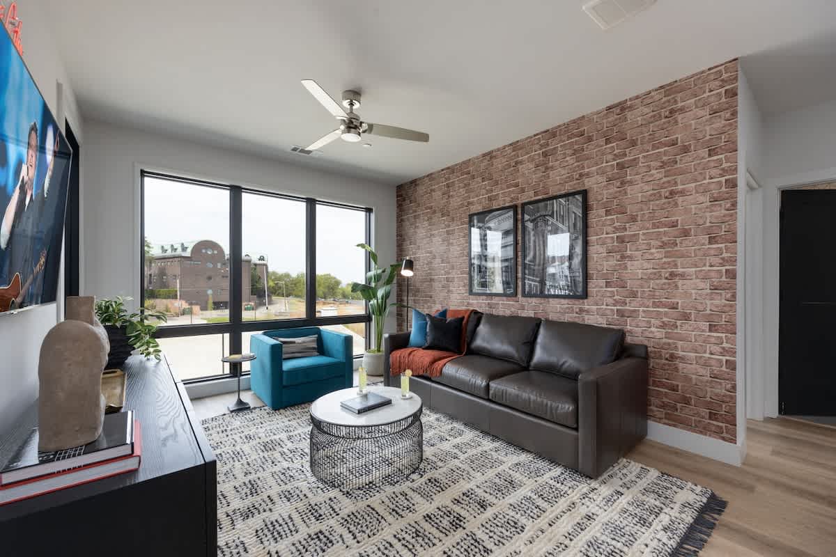 Inviting designer furnished living space featuring a comfortable sleeper sofa, a Smart TV for entertainment and a private covered balcony.