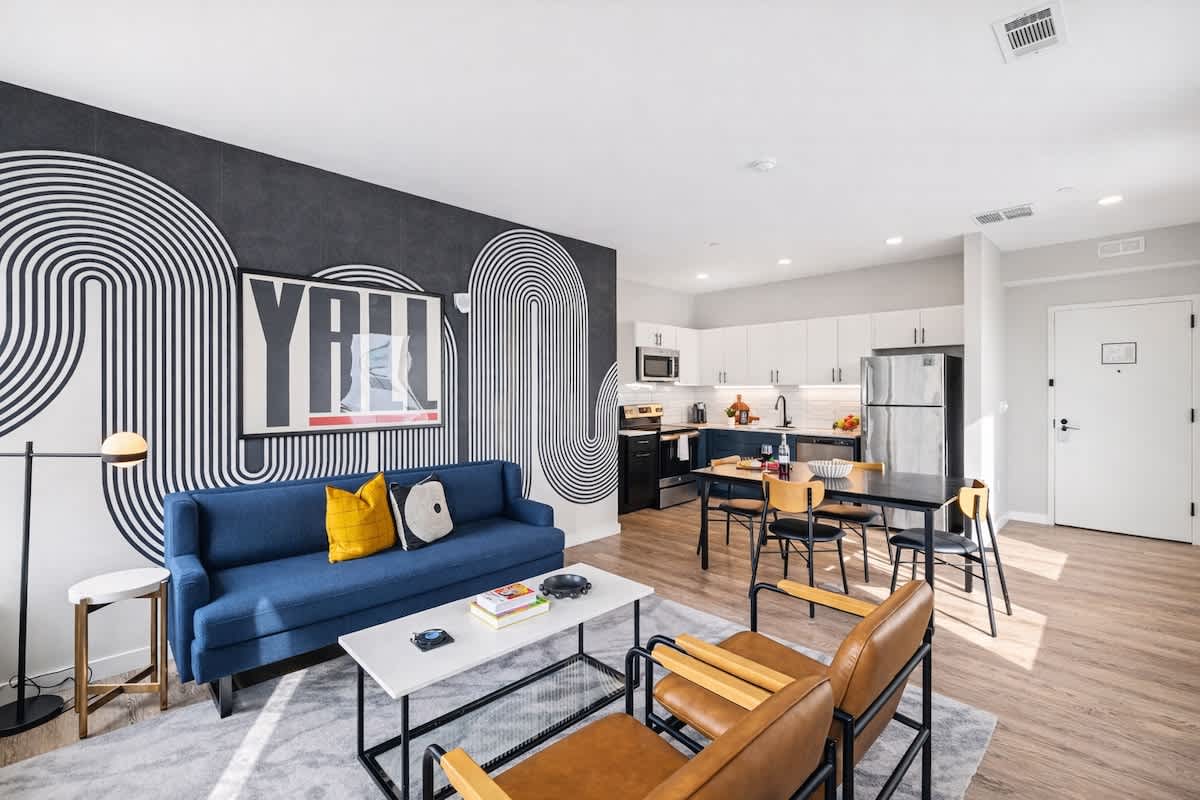 Bright open floor living space featuring a smart flat-screen TV and designer furnishings. Connects to the dining area and kitchen.