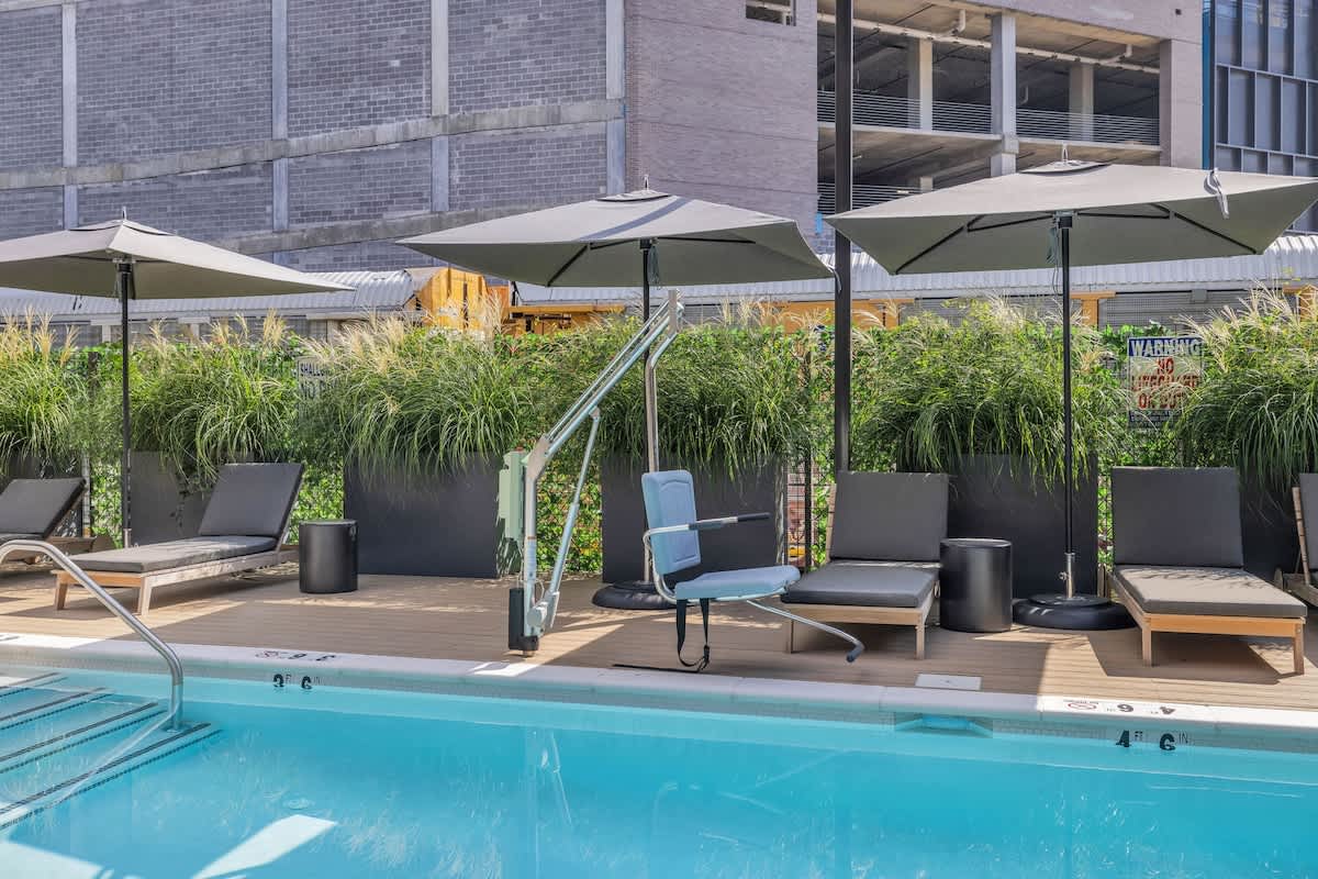 Communal Area: Sparkling blue pool with covered cabanas, sun loungers, and a wheelchair lift.