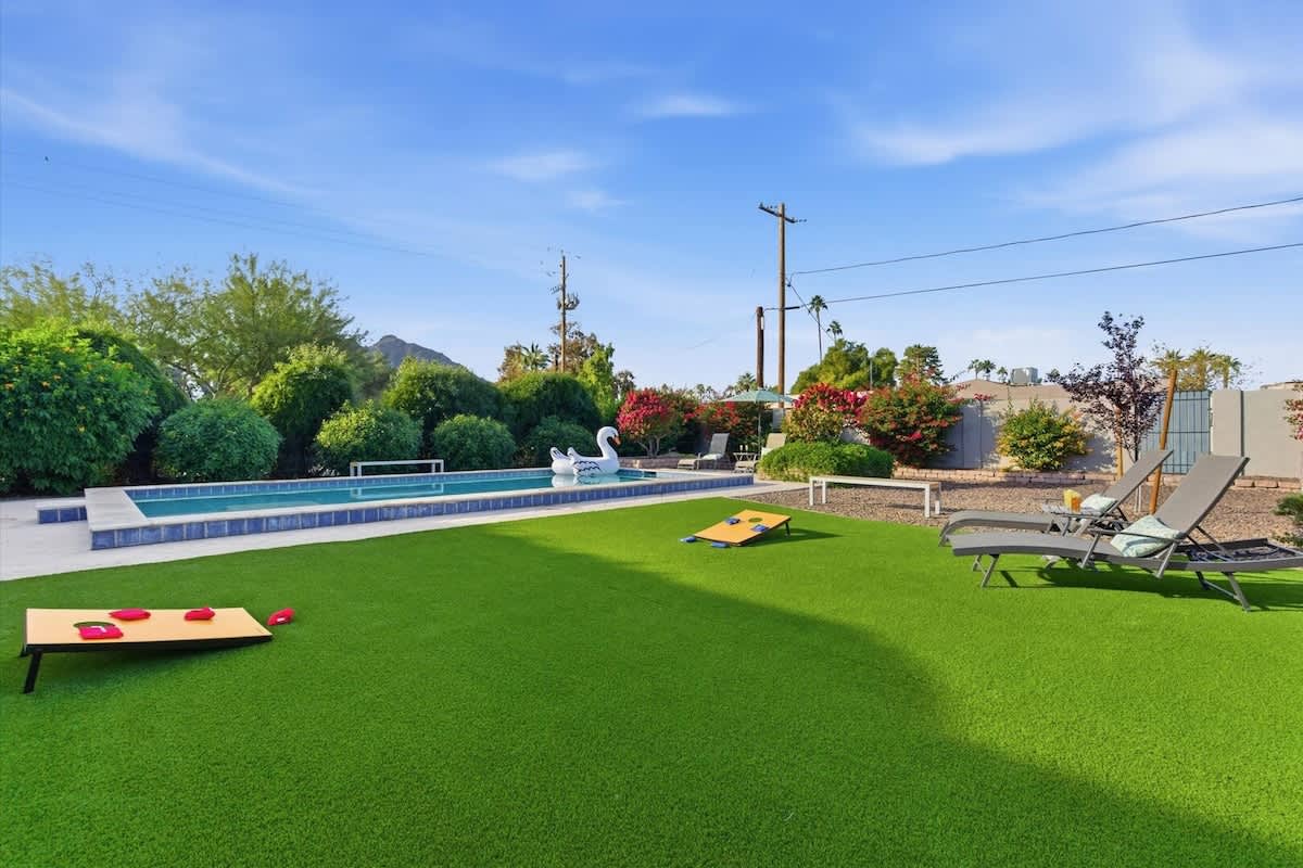 Private backyard with a sparkling pool, sun loungers, outdoor games, and a covered patio with an outdoor dining area and a BBQ grill.