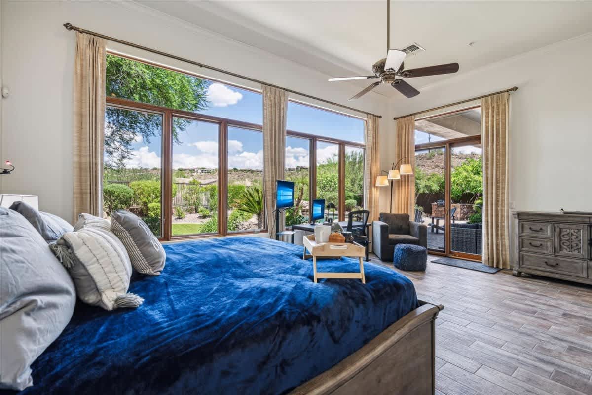 Primary Bedroom with a king bed, sofa chair, work station, en-suite bathroom and entrance to the backyard.