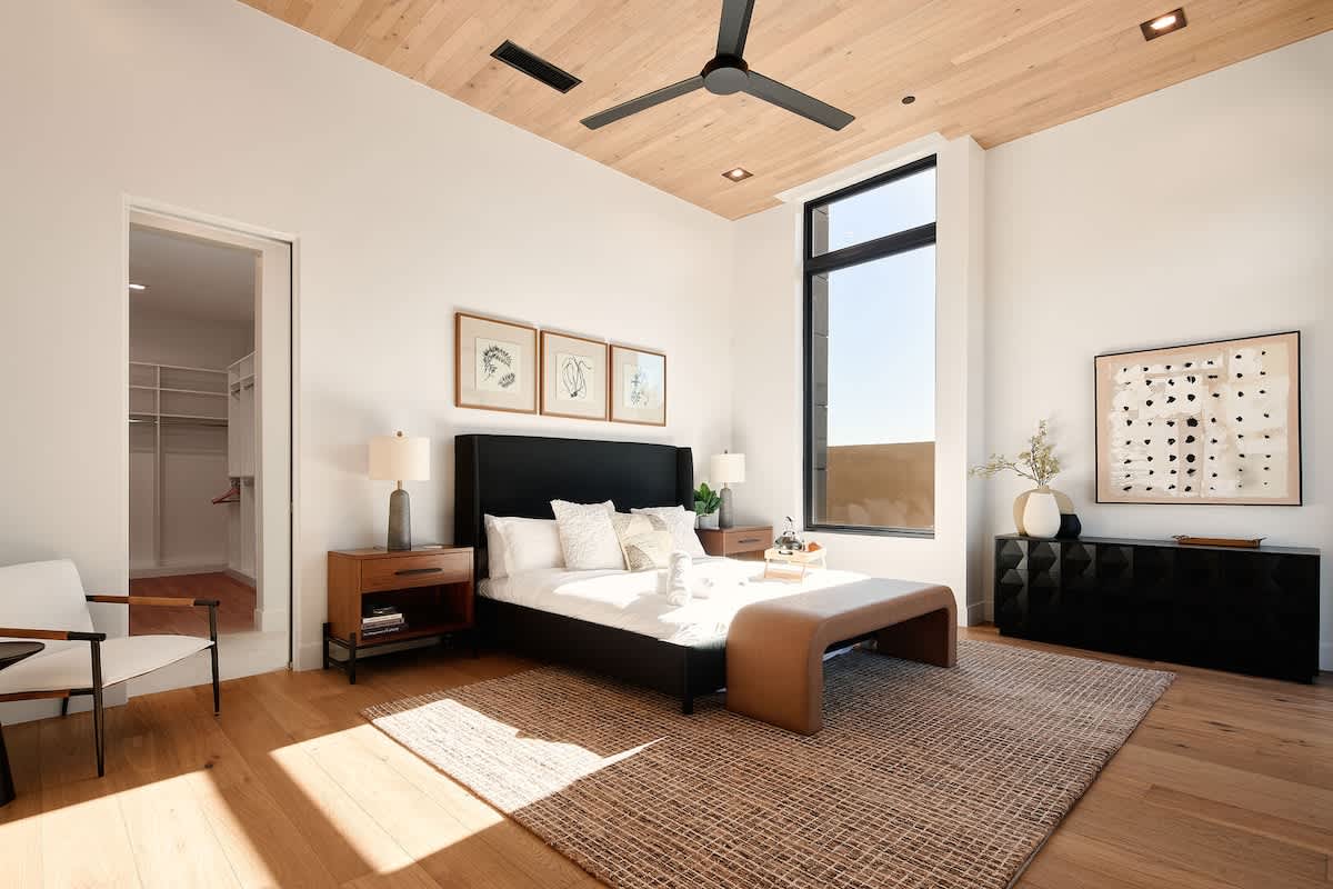 Primary bedroom featuring a King bed, plush furnishings, dresser, large walk-in closet, and an en-suite bathroom.