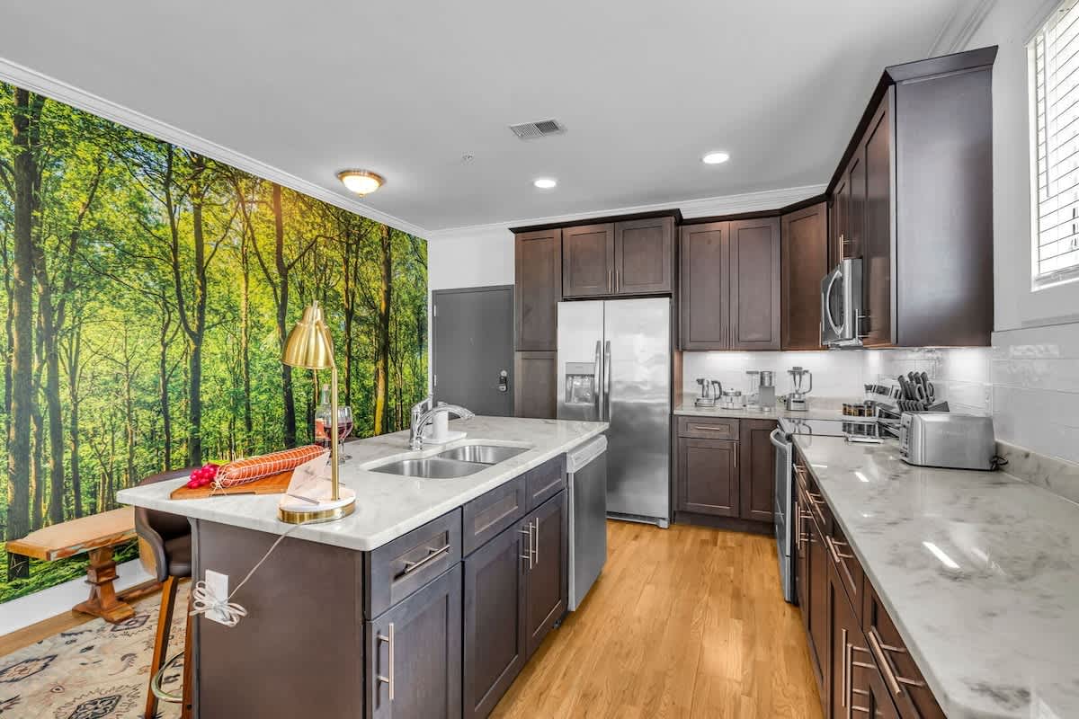 A fully equipped chef's kitchen features stainless steel appliances, culinary essentials, a kitchen island with bar seating, and ample counter space.