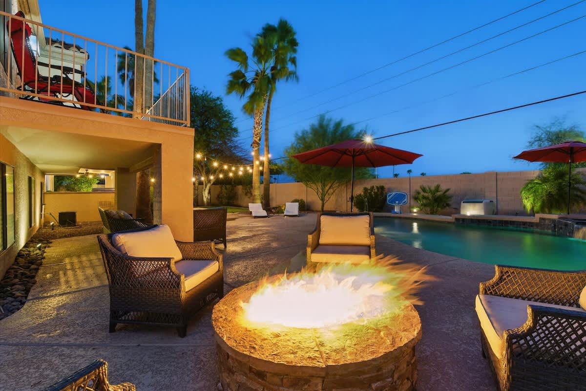 The private backyard is an entertainer’s dream with a pool, spa, fire pit, outdoor dining for six, built-in BBQ grill, hammock, pool loungers, cornhole, a large grassy area, and plenty of seating for 