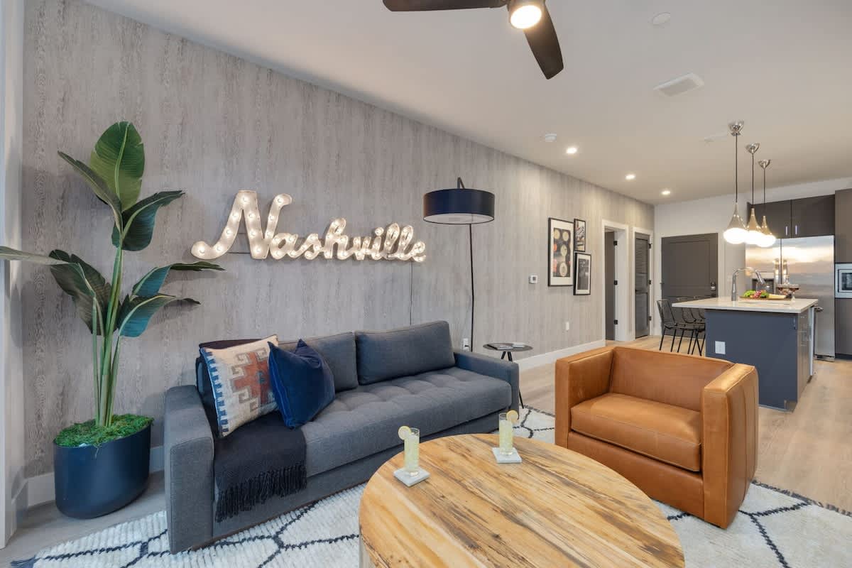 Open concept living area with smart TV, comfortable seating, designer decor, natural lighting, and access to private patio.