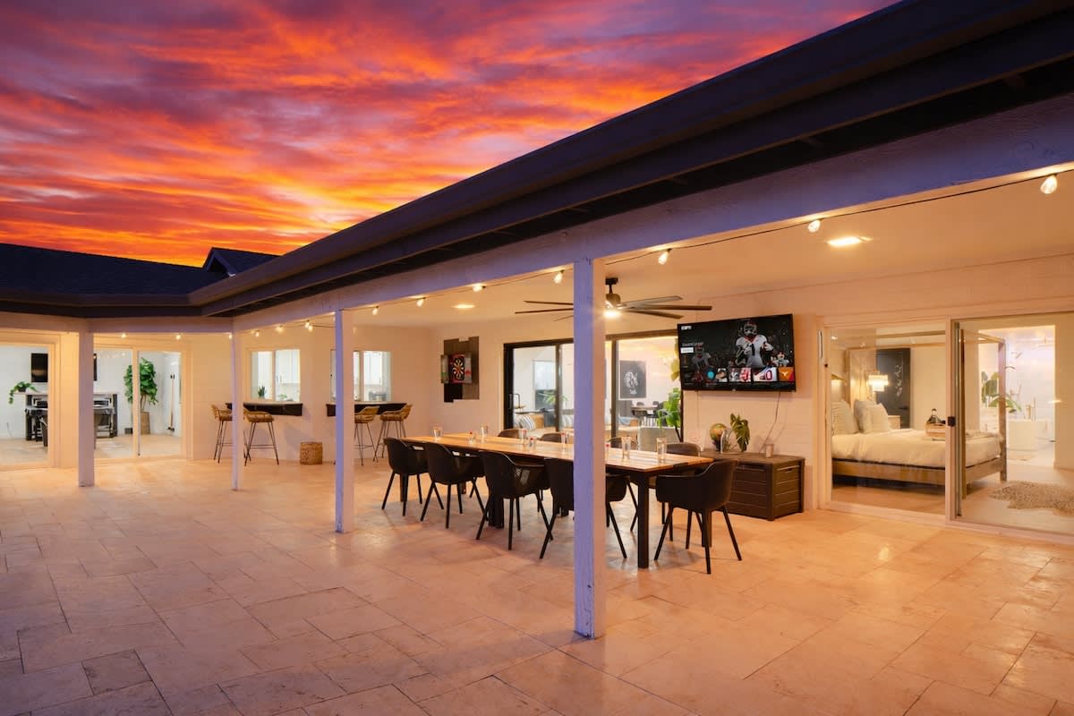 Resort-style backyard with a sparkling pool and hot tub, sun loungers, cozy outdoor seating, fire pit, mini golf, and cornhole, plus a covered patio with outdoor dining, bar seating, and a Smart TV.