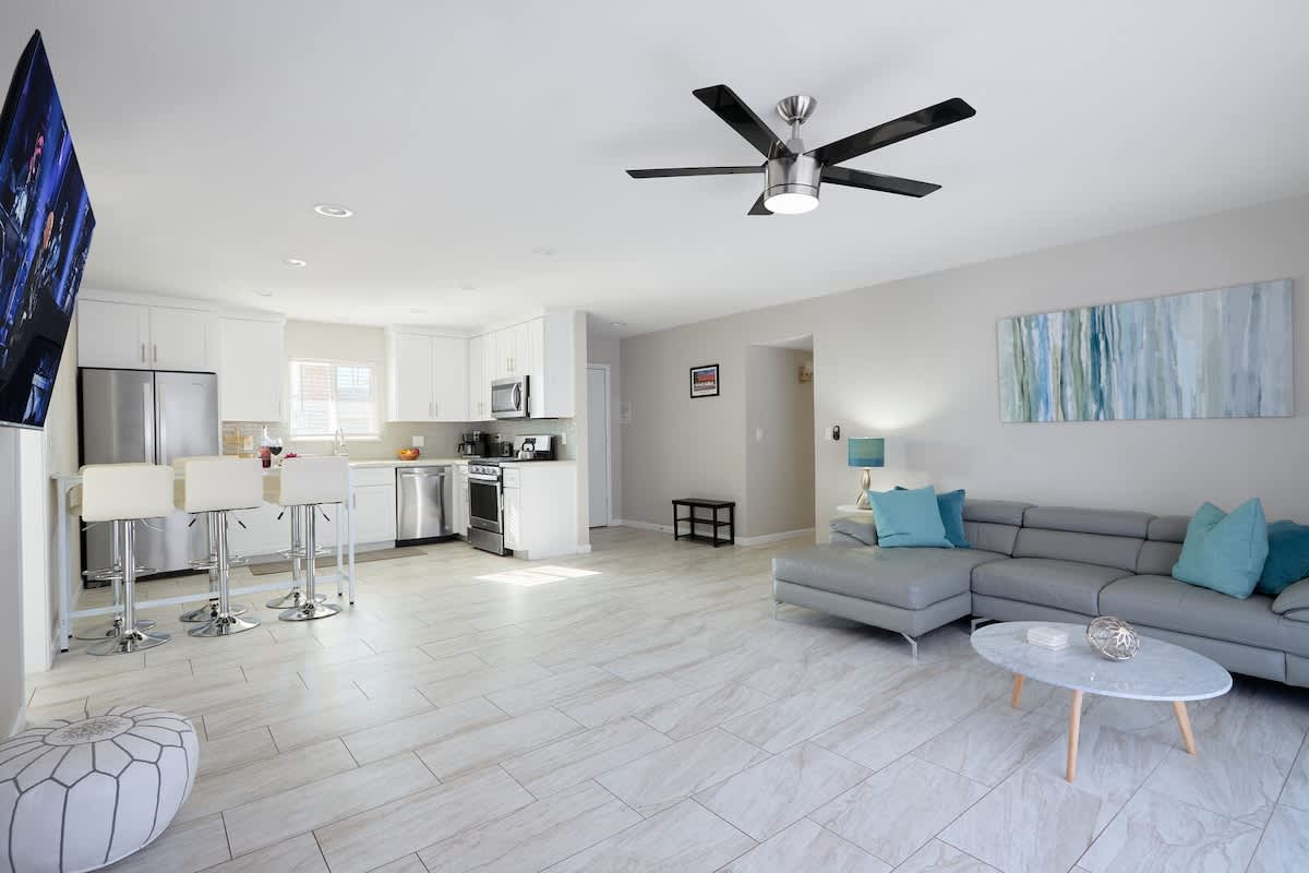 Open-concept living room with a cozy sectional, Smart TV, and sliding glass doors filling the space with natural light.