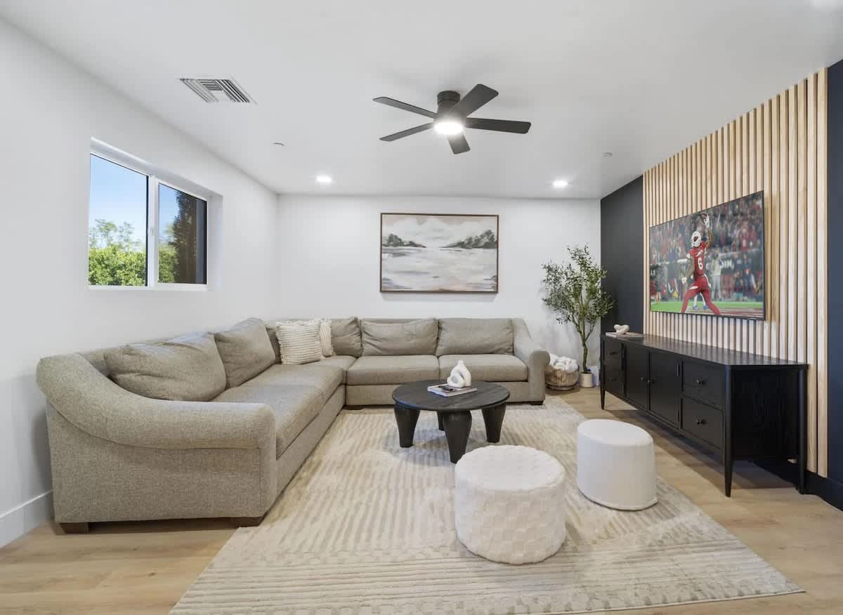 This stylish living room features a plush sectional, sleek media wall with a smart TV, and warm natural textures.