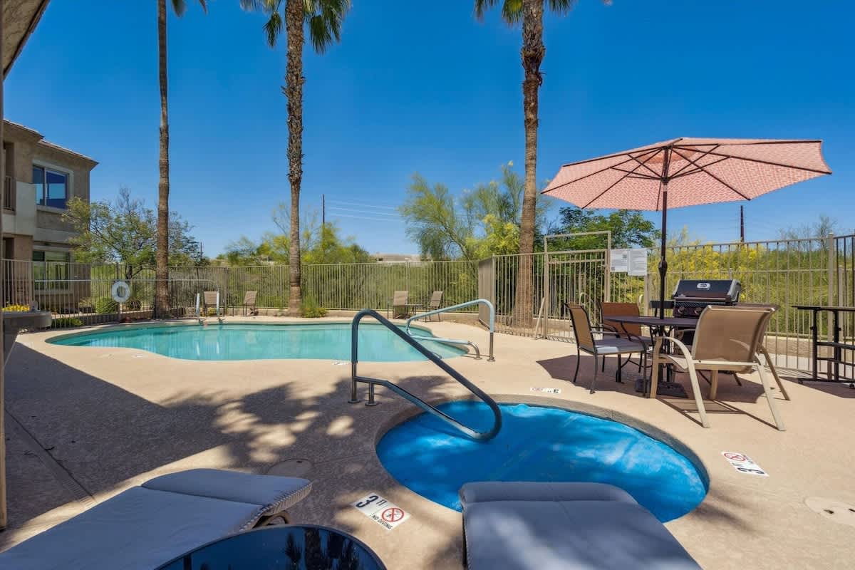 Communal Area: Relax and unwind in the Outdoor Oasis, featuring a pool, hot tub, grill, and comfortable seating.