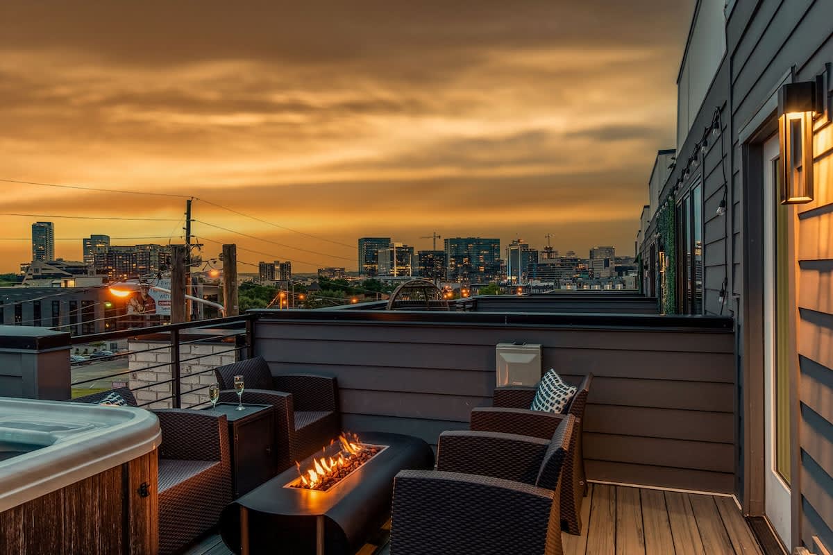 Private outdoor rooftop deck with stunning city views featuring a relaxing hot tub, firepit with outdoor furnishings, BBQ grill, and outdoor dining.
