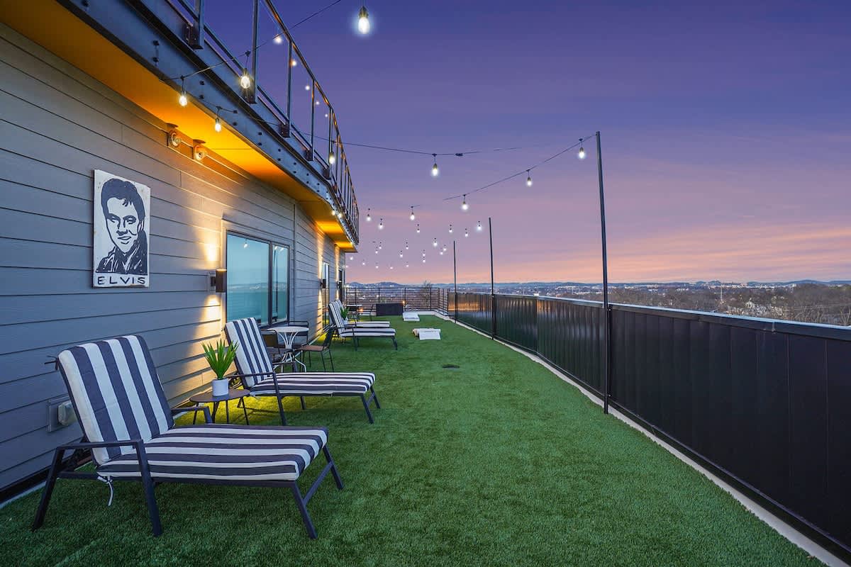 Expansive patio with stunning views of Downtown Nashville, plenty of outdoor seating, a hot tub, fire pit, outdoor dining area, sun loungers, and outdoor games.
