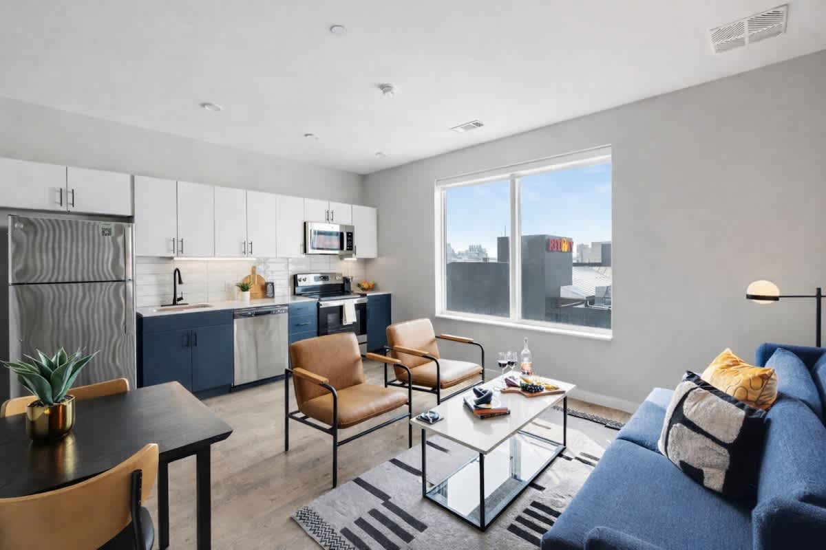 Bright open floor living space featuring a smart flat-screen TV and designer furnishings. Connects to the dining area and kitchen.