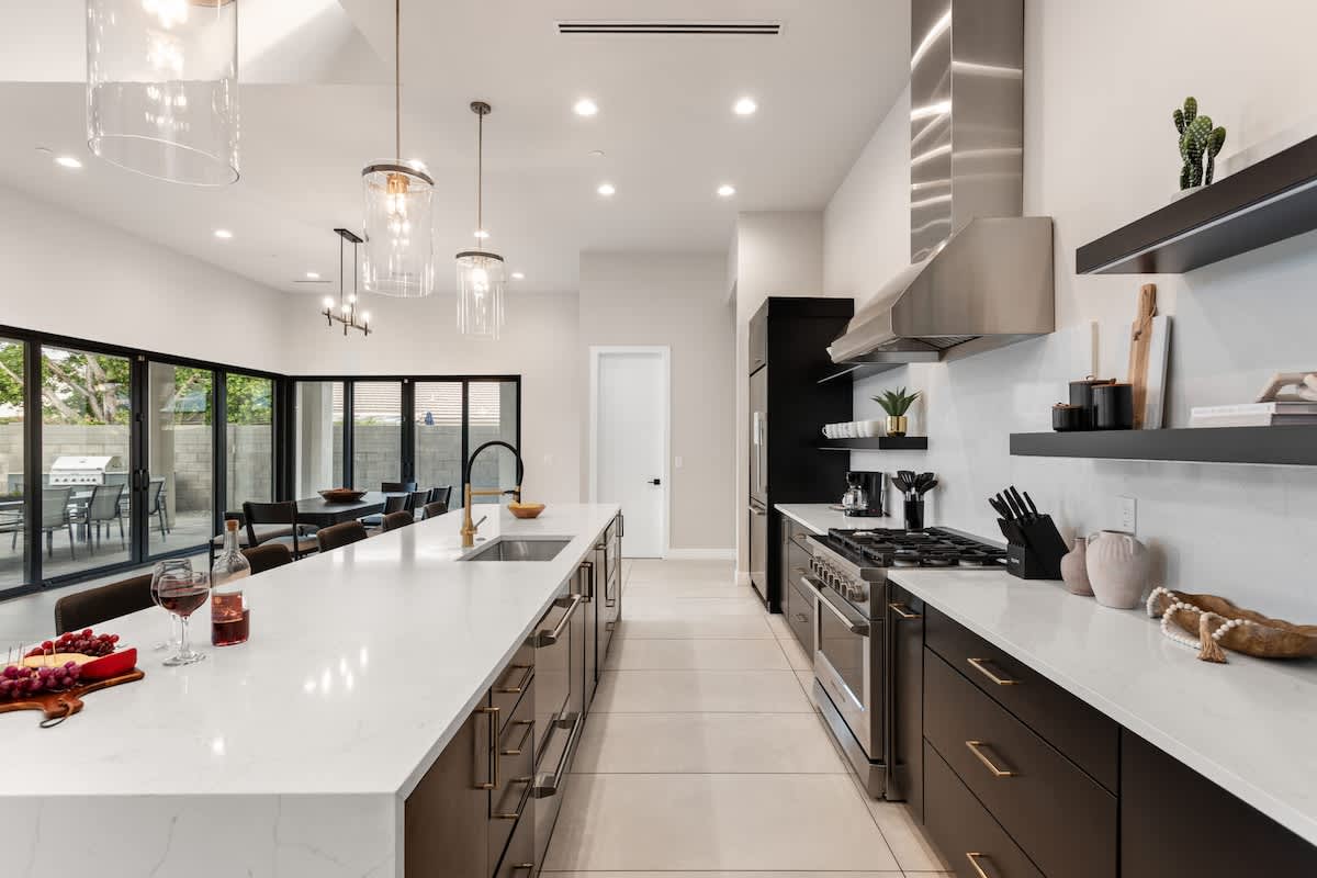 Large open-concept kitchen with brand new stainless steel appliances, quartz counter tops, large island with breakfast bar seating, and designer decor.