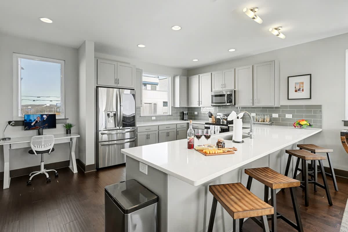 2nd Floor: Fully equipped kitchen with stainless steel appliances, ample counter space with seating for 4 guests, and a workstation with a monitor and desk chair.