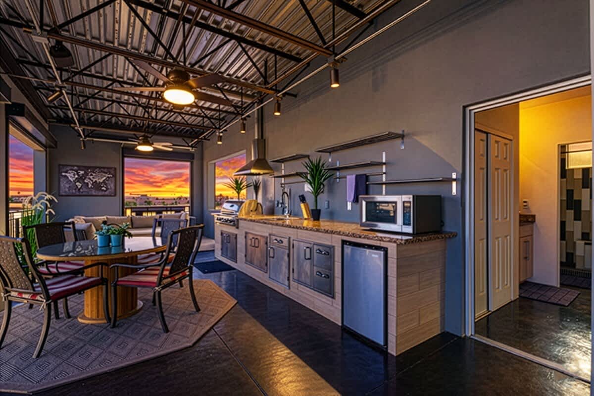 Rooftop deck boasts an outdoor kitchen with grill, sink, mini fridge, and cooking utensils, outdoor dining for four, a fireplace, smart TV, and three furnished lounging areas, and breathtaking panoram