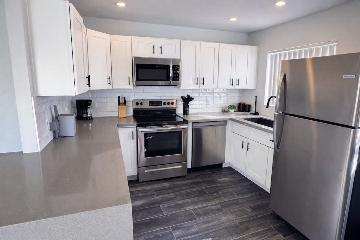 Fully equipped kitchen featuring stainless steel appliances, bar seating for 1 guest, and a dining area.